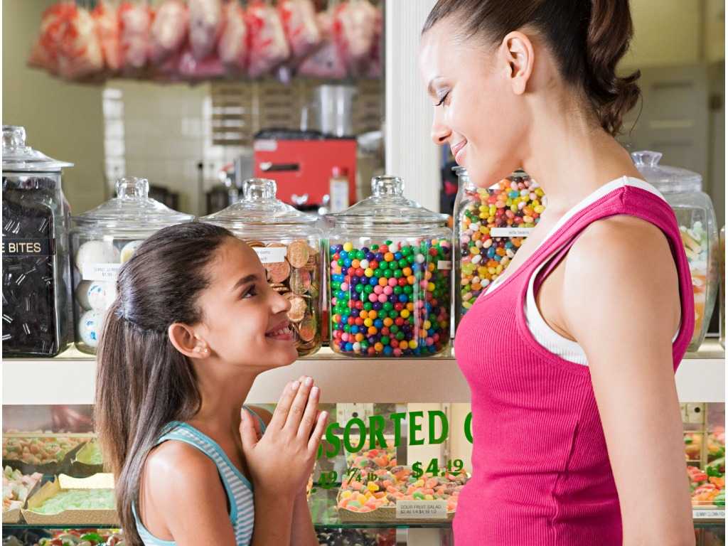 A daughter pleading to her mother for sweets from the sweet shop