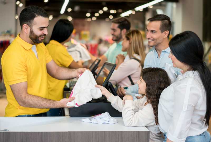 A young lady making a purchase at a store with her parents nearby