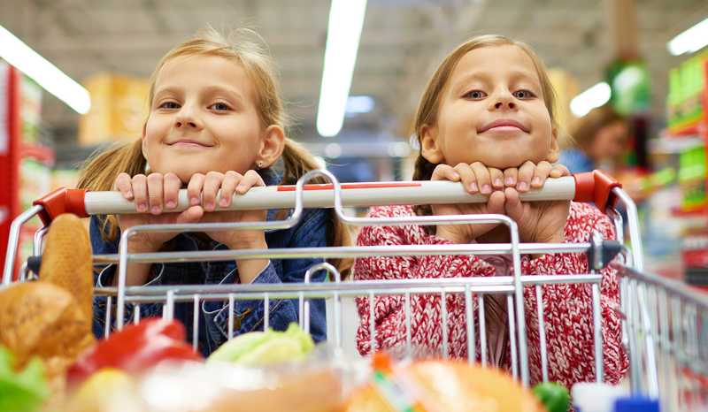 Two young girls pushing a shopping cart together