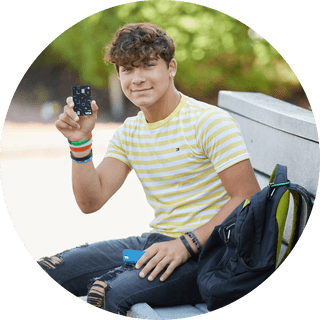 Teenager sitting on a bench and holding a Till debit card in one hand
